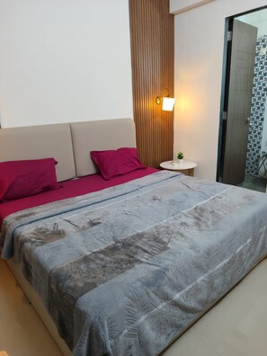 A modern bedroom with a bed, a nightstand, and a wall-mounted light fixture. - Peaceful 1-bedroom apartment with AC in vibrant Thane (Thane)