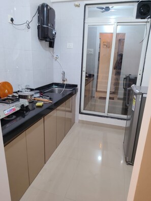 A compact kitchen with a built-in coffee maker, a kettle, and a toaster. - Peaceful 1-bedroom apartment with AC in vibrant Thane (Thane)