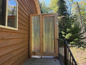 A wooden cabin with a sliding door and a small porch. - Turtle Cabin – Gichigami Island Properties 2 Bedrooms • 1 Bathroom • Sleeps 4 • Beach Access (La Pointe)