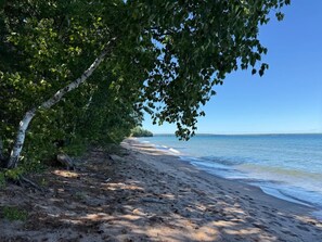 Ein Strand mit einem von Bäumen gesäumten Weg zum Wasser.