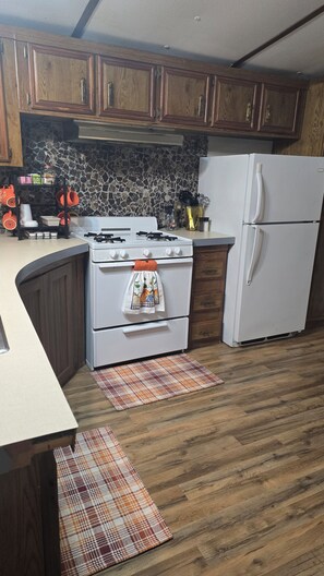 A kitchen with wooden cabinets, a white stove, a white refrigerator, and a stone backsplash.