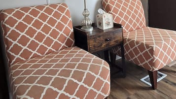 Une pièce avec deux canapés assortis, une lampe, une horloge et un plancher en bois.