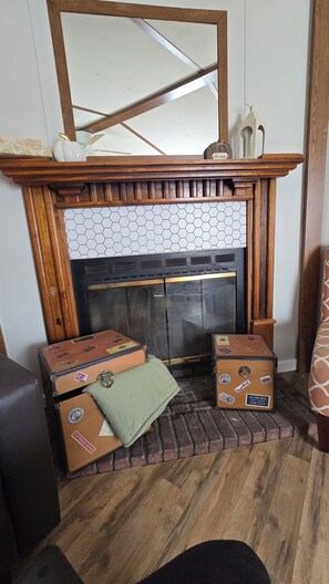 A fireplace with a wooden mantel, a tiled upper section, and two suitcases placed in front.