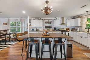A spacious kitchen with a large island, bar stools, and modern appliances. - Legacy Landing at Lake Guntersville (Guntersville)