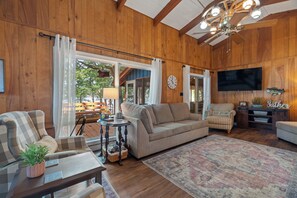 A cozy living room with a large sofa, a coffee table, and a television.