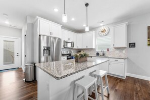 A modern kitchen with white cabinetry, stainless steel appliances, granite countertops, and a central island with bar stools. - Lakeview 3BR condo in Branson Cove with hot tub and pool access (Hollister)