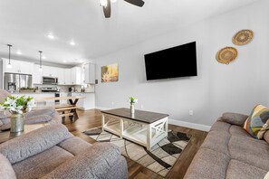 A modern living room with a dining table, sofas, and a kitchen in the background. - Lakeview 3BR condo in Branson Cove with hot tub and pool access (Hollister)