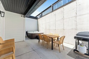 An outdoor patio with a wooden table and chairs, a hot tub, and a grill. - Lakeview 3BR condo in Branson Cove with hot tub and pool access (Hollister)
