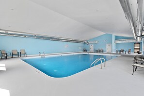 A large indoor swimming pool with clear blue water, surrounded by lounge chairs and a seating area with tables. - Lakeview 3BR condo in Branson Cove with hot tub and pool access (Hollister)