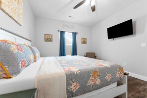 A bedroom with a bed, a ceiling fan, a flat-screen TV, and a window with curtains. - Lakeview 3BR condo in Branson Cove with hot tub and pool access (Hollister)