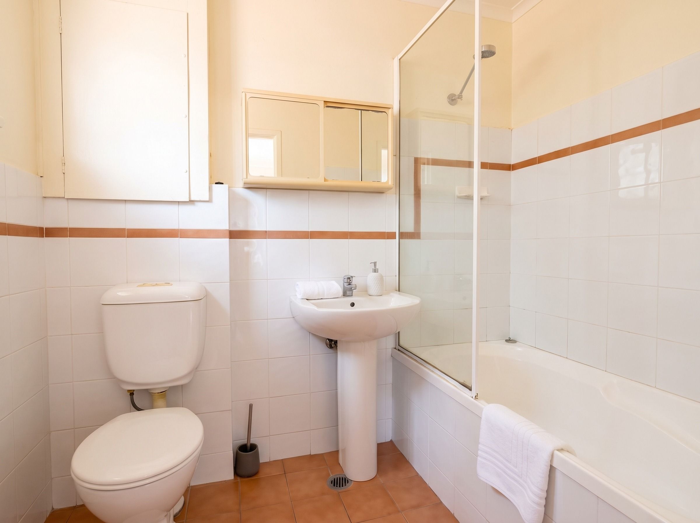 Une salle de bain avec des toilettes, un lavabo et une douche.
