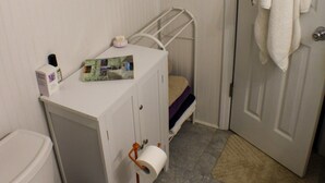 Et lille badeværelse med toilet, vask og bruseområde.