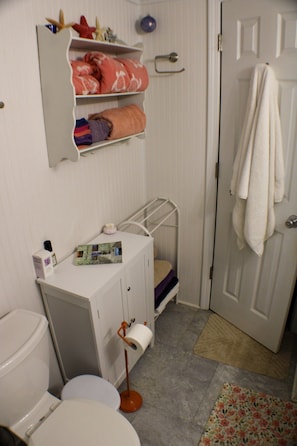 A small bathroom with a toilet, sink, and a shower area. - Half & Half Cottage By the Sea 1.6 miles to Holden Beach (Supply)