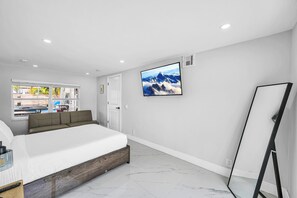 A bedroom with a bed, a TV mounted on the wall, and a window with a view of the outside. - The Coastal Retreat. Spacious 5-bedroom House Near Ocean, Heated Pool And Studio (Pompano Beach)