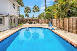 A swimming pool with a wooden deck, a seating area with a table and chairs, and a wooden fence surrounding the property. - The Coastal Retreat. Spacious 5-bedroom House Near Ocean, Heated Pool And Studio (Pompano Beach)