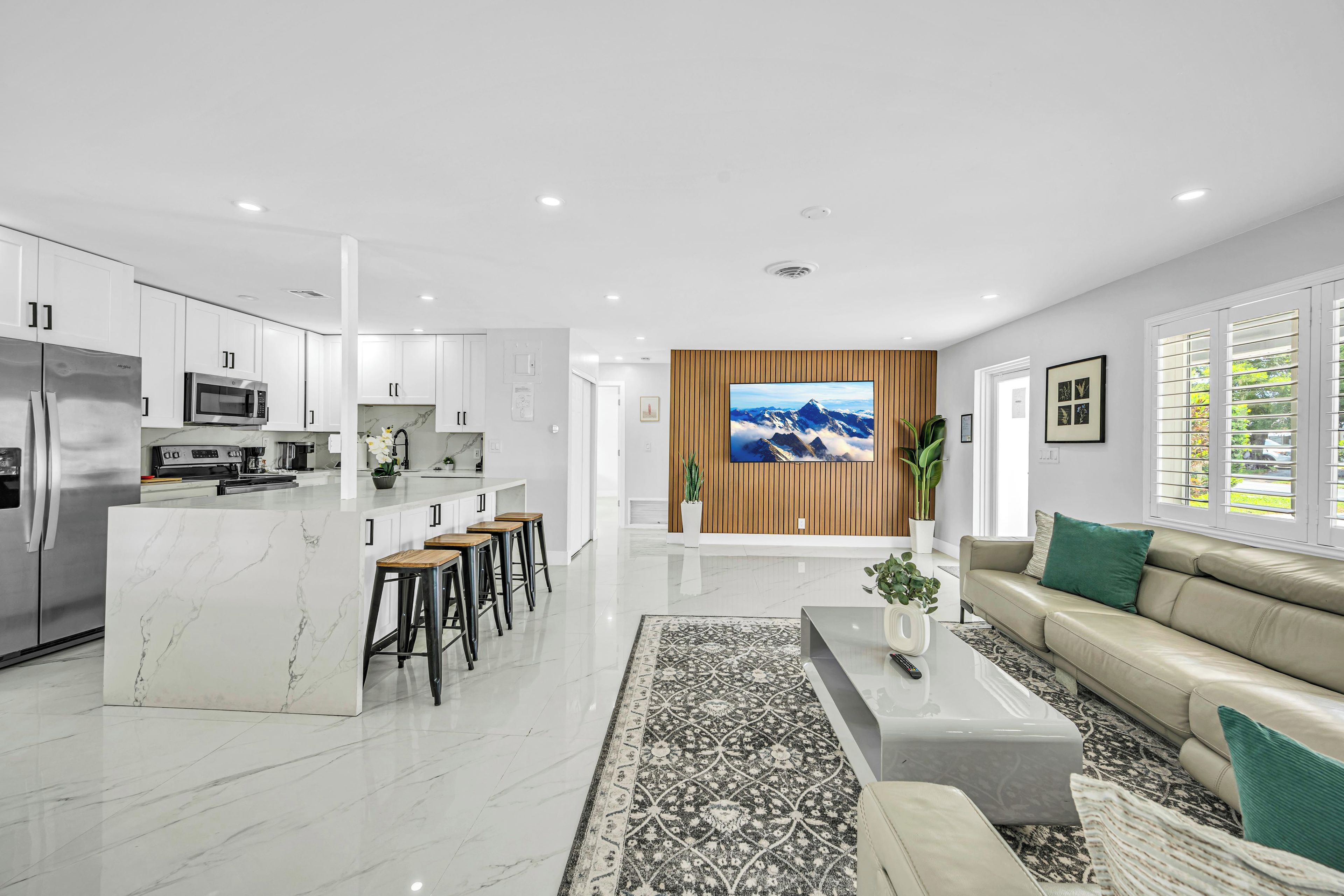 Una cocina moderna con armarios blancos, un refrigerador de acero inoxidable y un microondas.