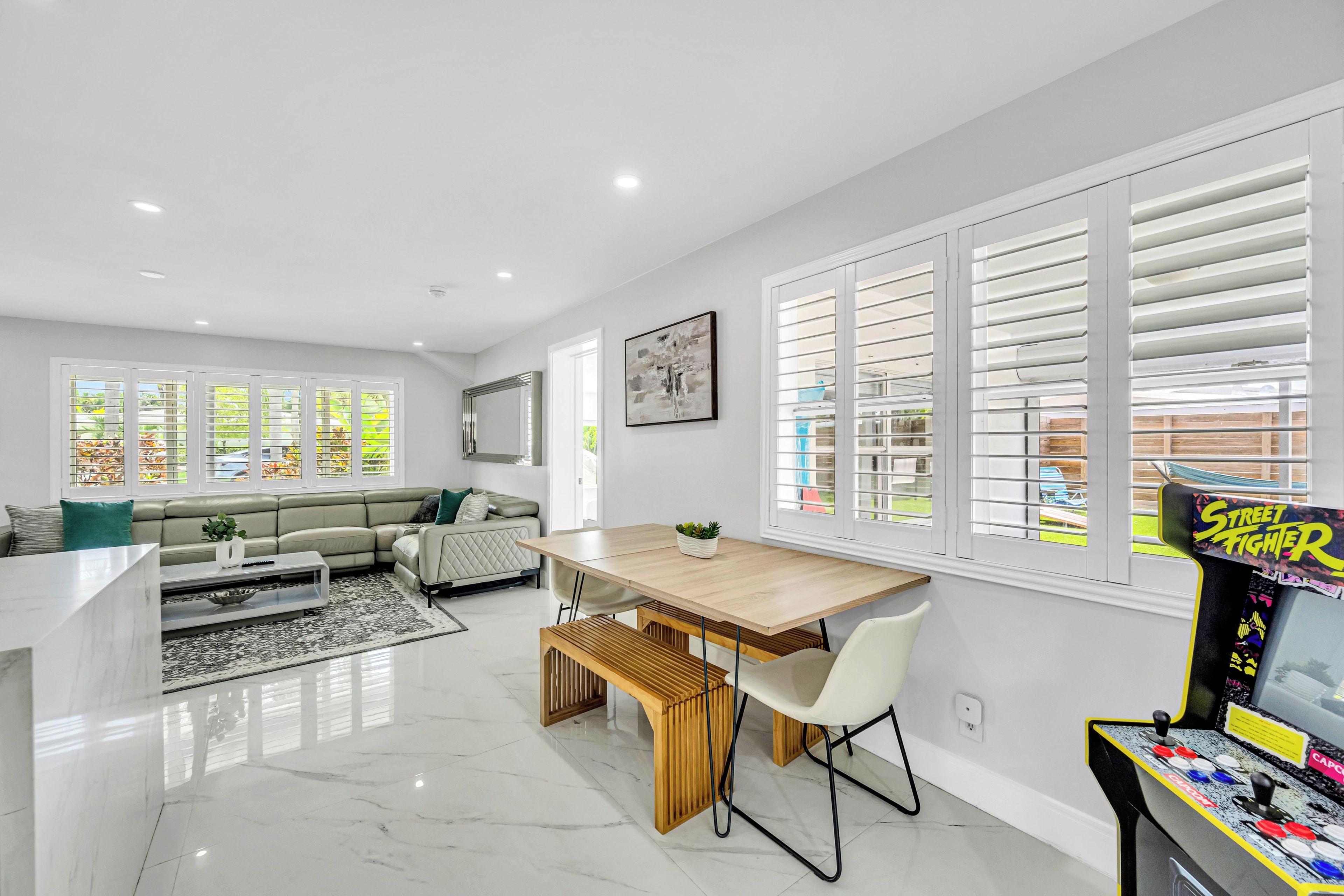 A modern living space with a dining area, a sofa, a coffee table, and a gaming console.