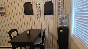 A dining area with a table and chairs, a water dispenser, and wall-mounted wine glasses. - Beach Retreat Oceanview Balcony (North Topsail Beach)