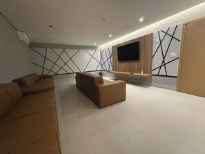 A modern living room with a sectional sofa, a coffee table, and a flat-screen TV mounted on the wall.
