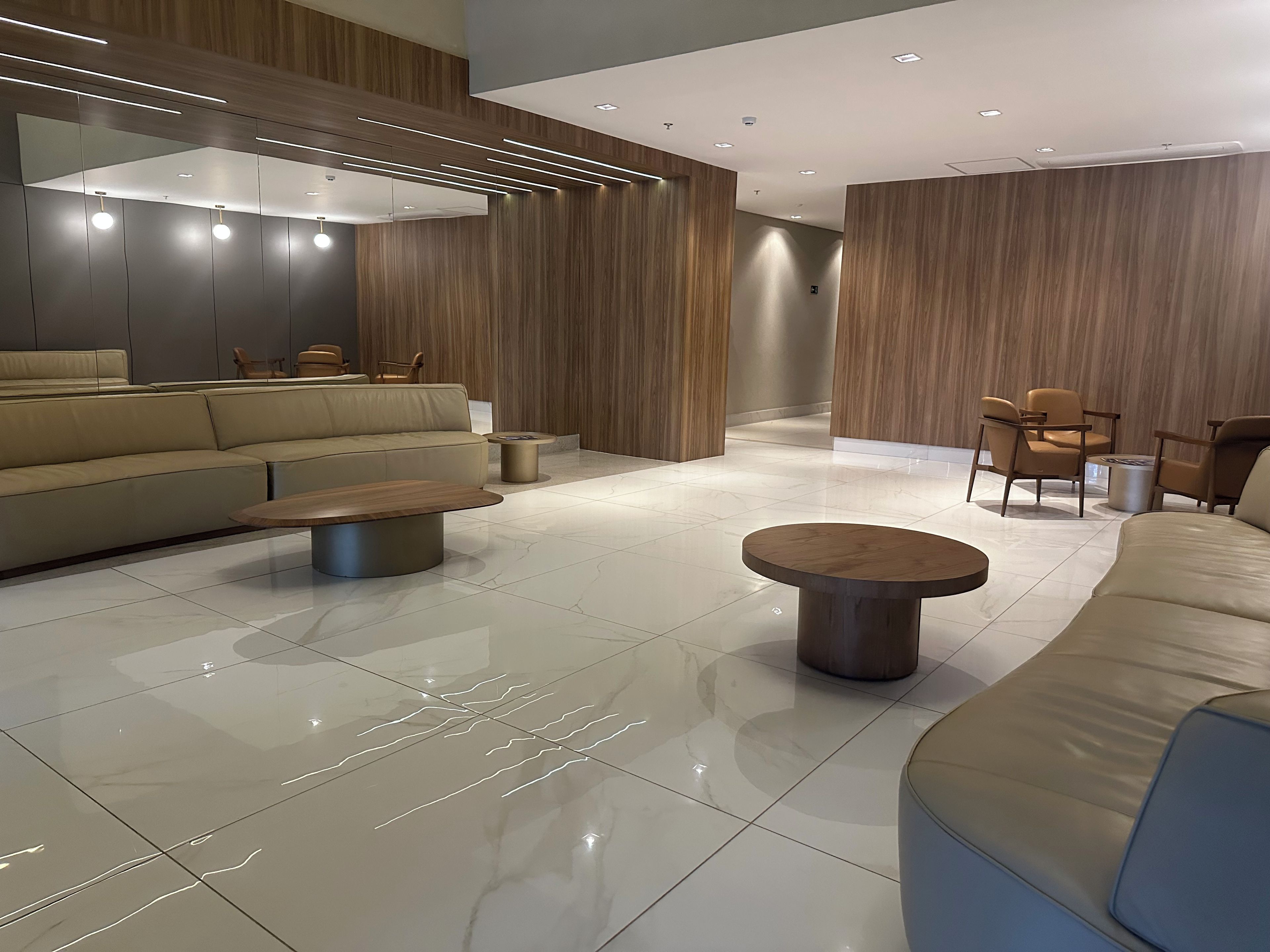 A modern interior with a sofa, coffee table, and chairs, featuring wooden paneling and recessed lighting.