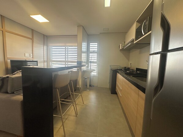 A modern kitchen with a refrigerator, stove, and bar stools.