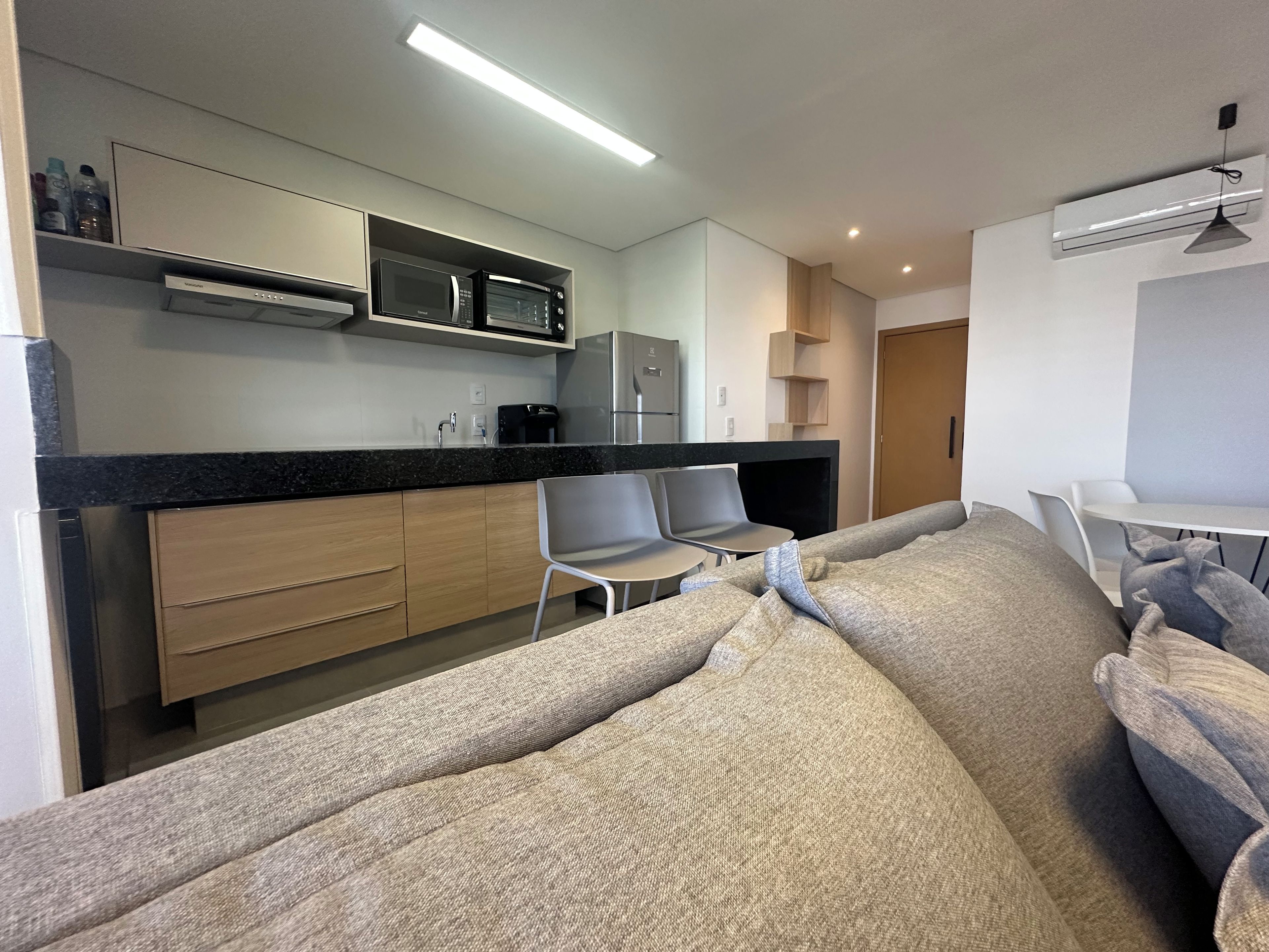 A modern kitchen with built-in appliances, a dining area with a sofa, and a small table.