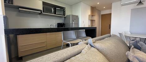 A modern kitchen with built-in appliances, a dining area with a sofa, and a small table.