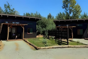 Un edificio con un área exterior techada, un sendero pavimentado y una valla de madera.