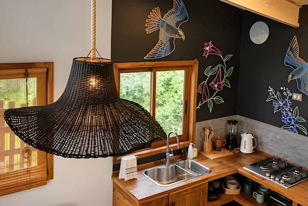 A kitchen with a hanging light fixture, a sink, and decorative wall art.