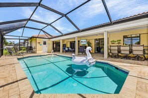 A swimming pool with a sunshade structure, lounge chairs, and a sign for 'Rosen's Vacations'. - Poolside Escape for Family Fun in Sunny Cape Coral Getaways - Country Club Villa - Roelens (Cape Coral)