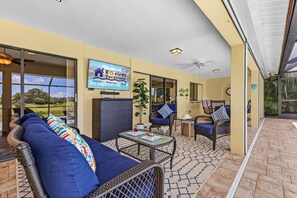 A covered outdoor seating area with wicker furniture, a table with a cake, and a sign for 'Rocelens Vacations'. - Poolside Escape for Family Fun in Sunny Cape Coral Getaways - Country Club Villa - Roelens (Cape Coral)