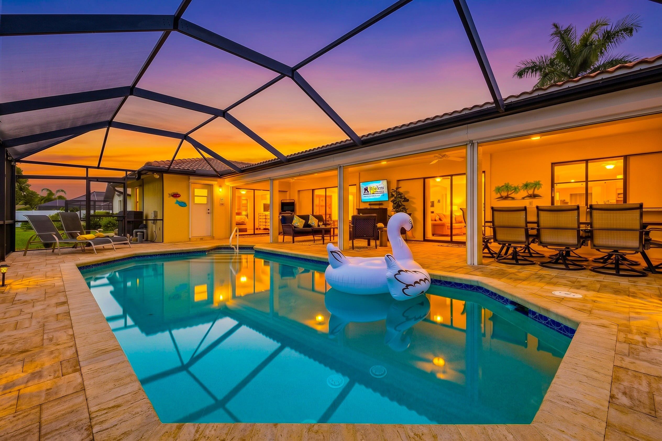 An indoor swimming pool with a swan float, lounge chairs, and a restaurant area with outdoor seating.