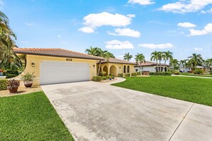 A residential property with a garage, a well-maintained lawn, and a clear sky. - Poolside Escape for Family Fun in Sunny Cape Coral Getaways - Country Club Villa - Roelens (Cape Coral)