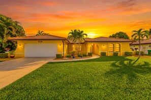A residential property with a well-maintained lawn, a garage, and a driveway leading to the entrance. - Poolside Escape for Family Fun in Sunny Cape Coral Getaways - Country Club Villa - Roelens (Cape Coral)