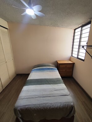 A bedroom with a bed, a ceiling fan, a window with bars, a wardrobe, and a wooden dresser. - Extraordinary house in Los Pinos, Morelia (wheelchair accessible). (Morelia)