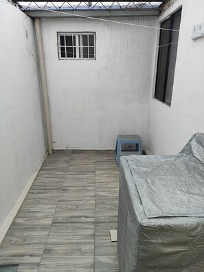 A small, enclosed room with a tiled floor, a window, and a bed covered with a protective sheet. - Extraordinary house in Los Pinos, Morelia (wheelchair accessible). (Morelia)