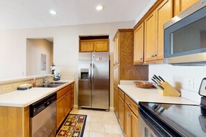 A kitchen with wooden cabinets, stainless steel appliances, a microwave, and a dish rack. - Aerie Retreat | Mtn Views, Near Sugar Ski Resort (Sugar Mountain)