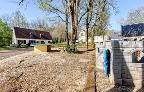 A building with a stone wall and a blue door, a bench, and a table in a park-like setting. - Lovely home in Carlux with heated swimming pool (Carlux)
