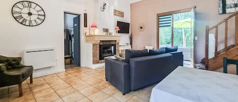 Una sala de estar moderna con chimenea, un sofá, una mesa de comedor y un reloj en la pared.