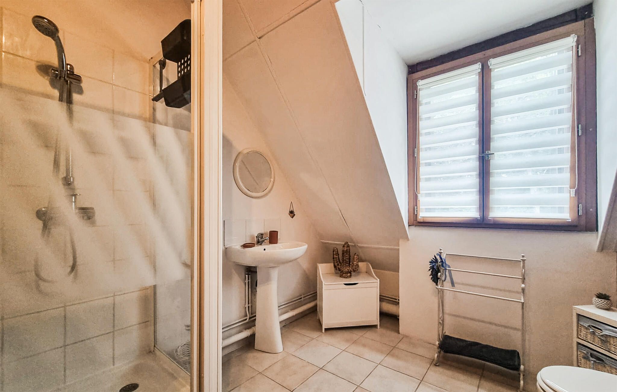 A bathroom with a shower, sink, and window.