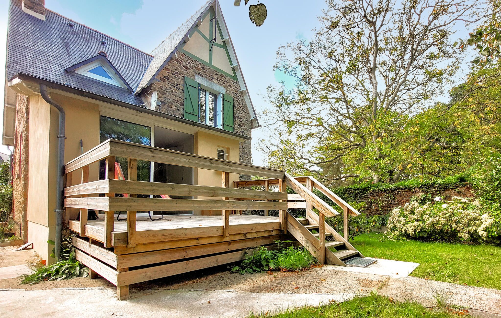 Une maison à deux étages dotée d’une terrasse en bois et d’un escalier menant à l’étage supérieur.