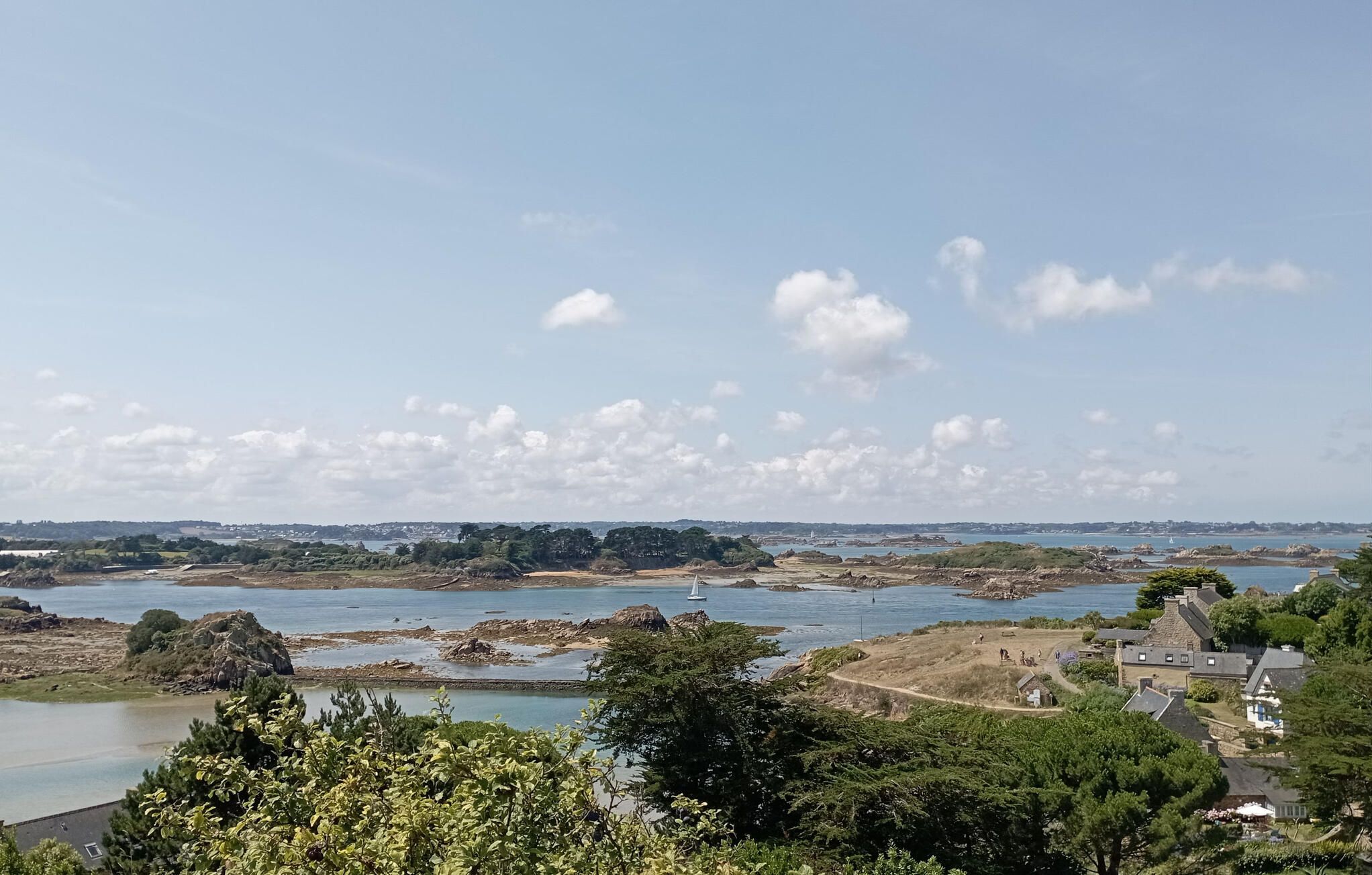Een kustlandschap met rotsachtige oevers, een heldere lucht en een vergezicht op een stad.