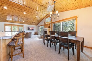 A spacious kitchen with wooden ceiling beams, large windows, and a dining area with wooden chairs and a table. - Monthly Lease - Bellflower at Tahoe Donner by Tahoe Getaways - Pet-Friendly 4BR w EV Charger & HOA (Truckee)
