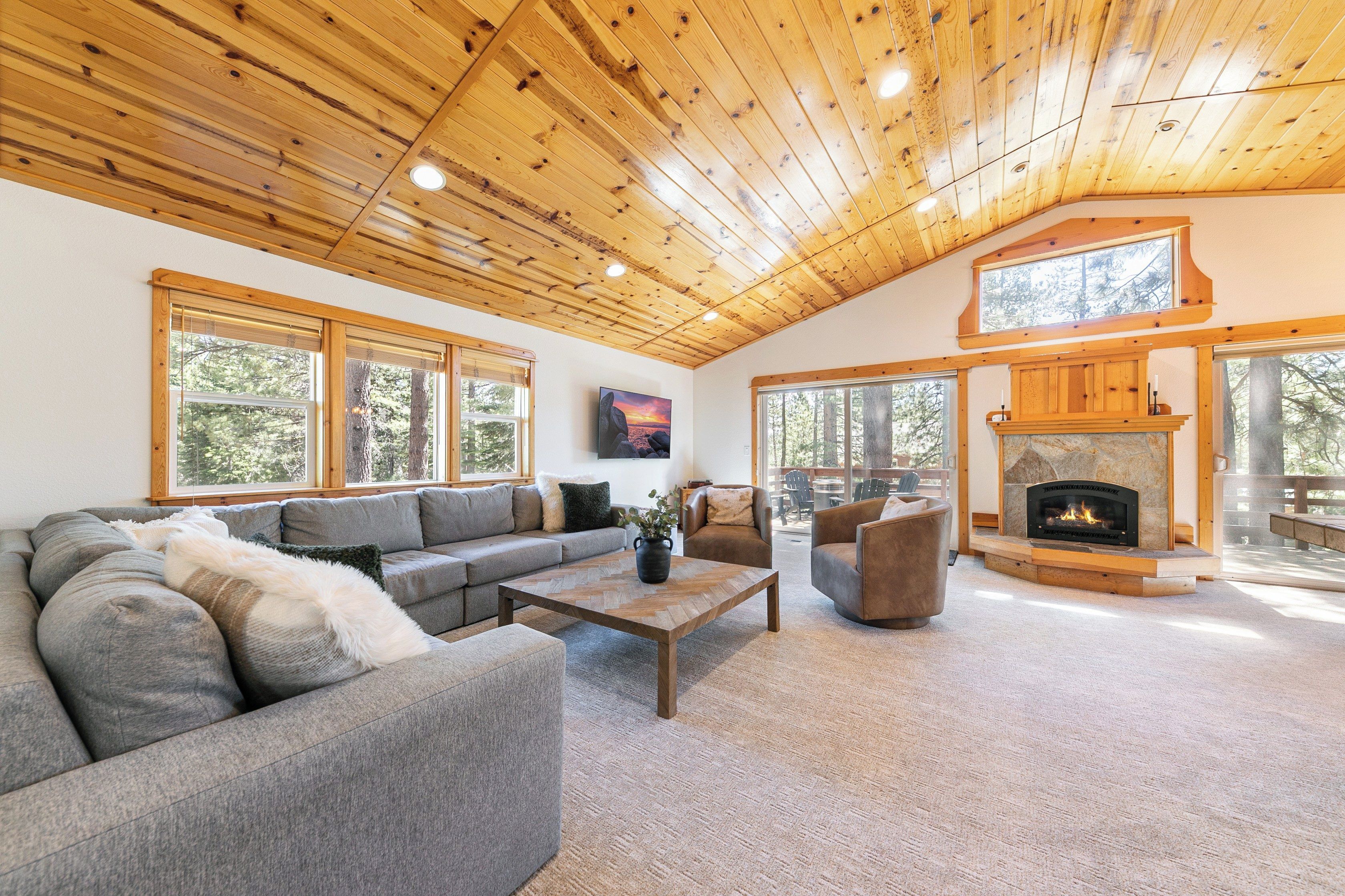 Un salon spacieux avec un plafond en bois, une cheminée et de grandes fenêtres.