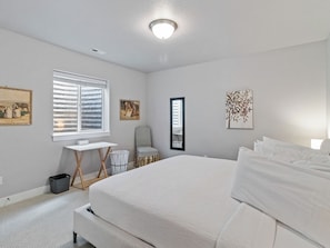 A bedroom with a large bed, a desk, a chair, and a window with blinds. - Midway 447 | Golf Views | Gym | Pool & Hot Tub | Near Deer Valley (Midway)