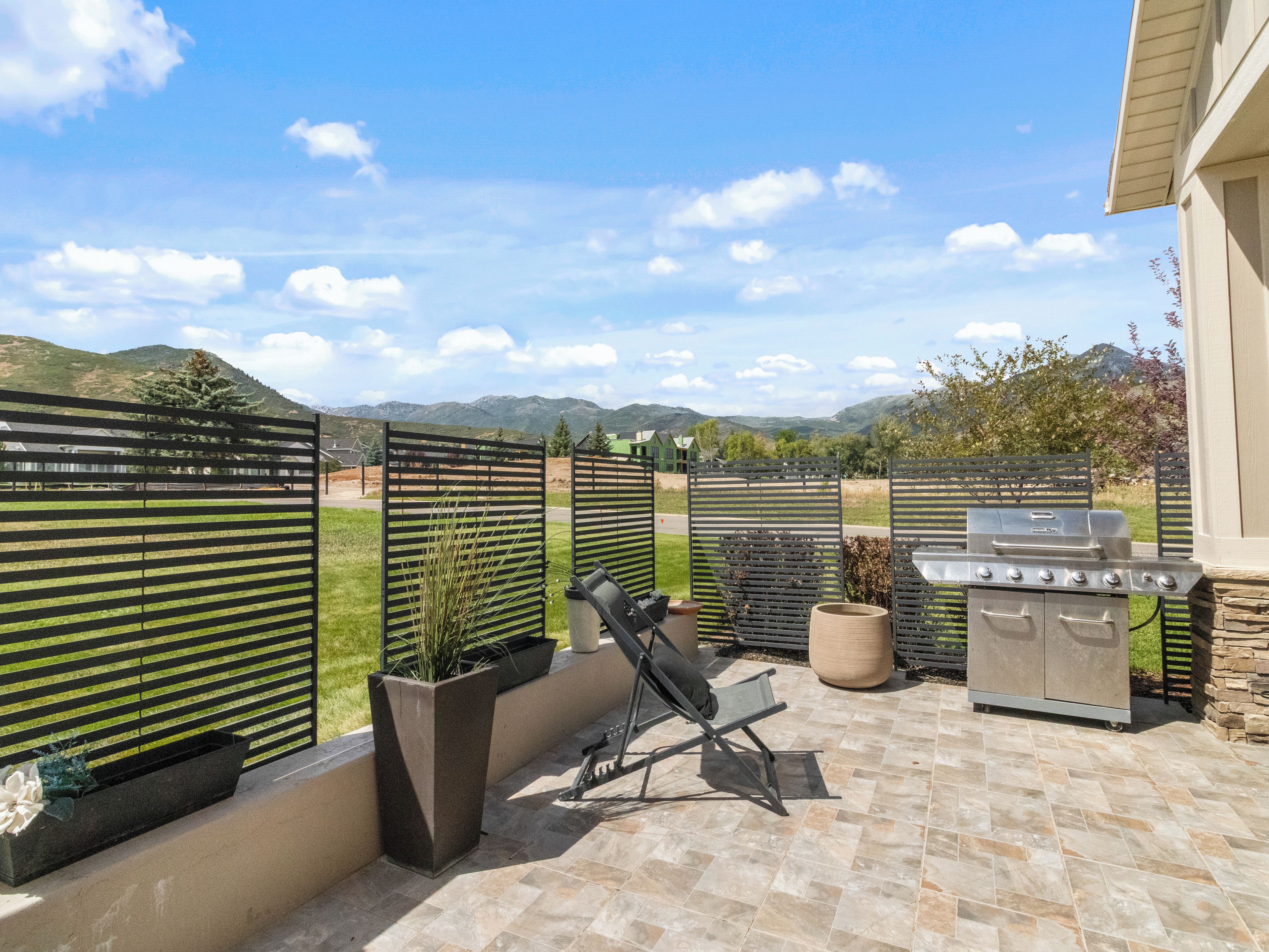 Une terrasse extérieure équipée d’un barbecue, de sièges et offrant une vue sur les montagnes.