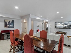 A modern dining room with a wooden table and red upholstered chairs, a piano, and a large painting on the wall. - Midway 447 | Golf Views | Gym | Pool & Hot Tub | Near Deer Valley (Midway)