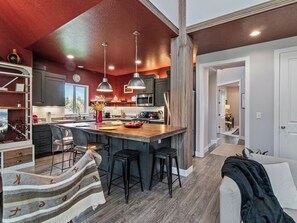 A modern kitchen with a central island, bar stools, pendant lighting, and a view of the outdoors. - Midway 447 | Golf Views | Gym | Pool & Hot Tub | Near Deer Valley (Midway)