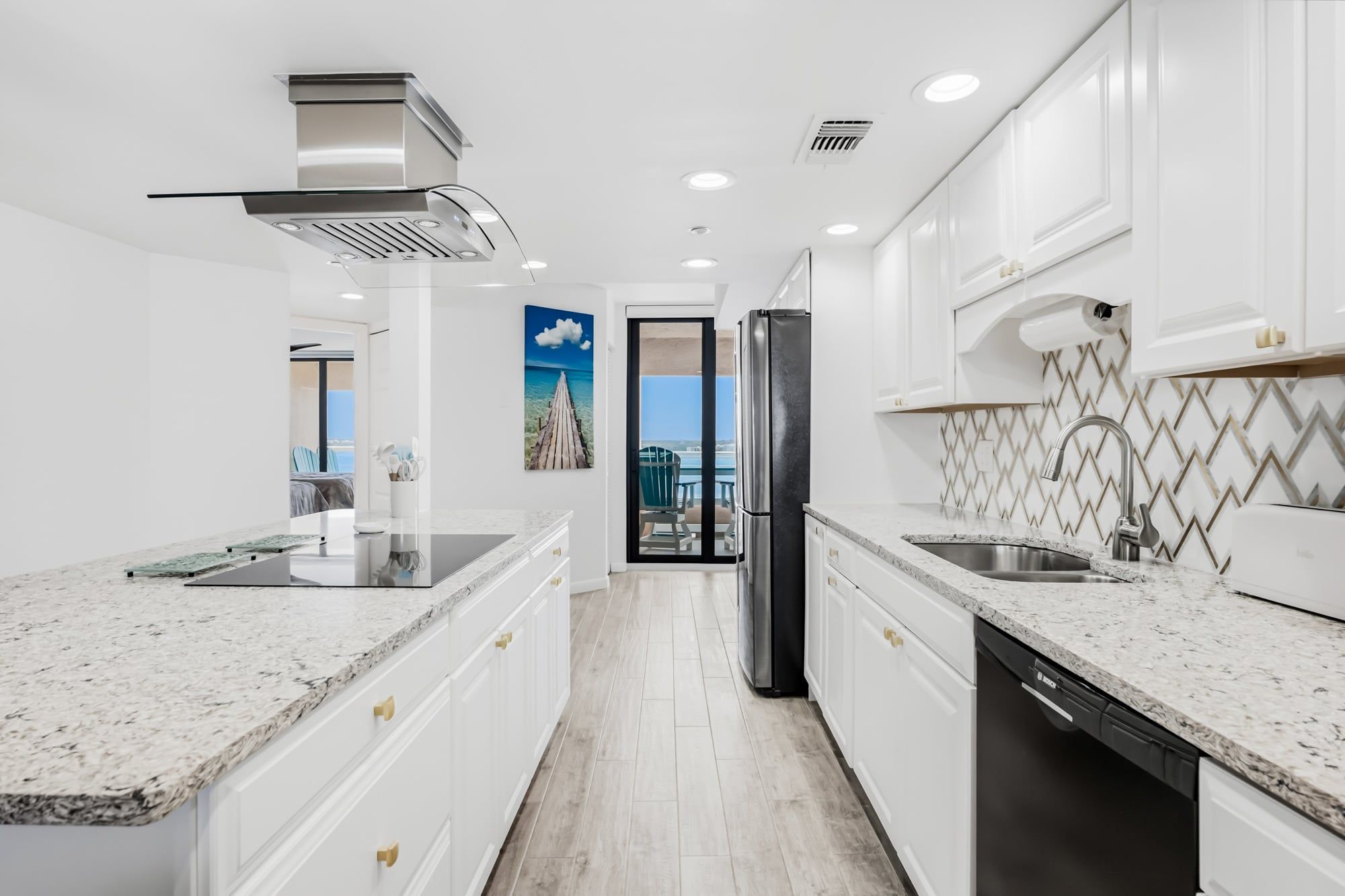 A modern kitchen with white cabinetry, granite countertops, a stainless steel refrigerator, and a dishwasher.