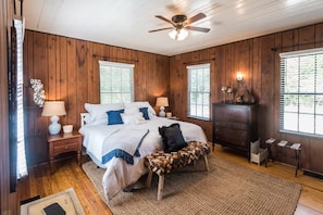 A bedroom with a bed, nightstands, a dresser, and a ceiling fan. - 1929 Creek House at HollyOaks on the Marsh (Savannah)
